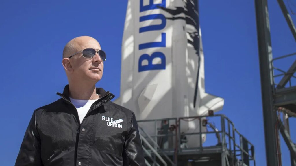 Jeff Bezos wearing glasses and blue origin in the background