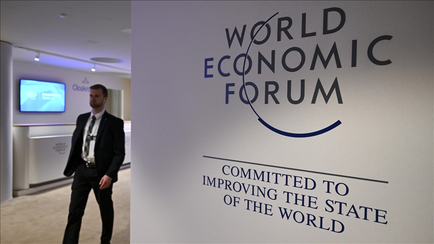 Man in black suit standing with World Economic Forum 2024 Sign Board